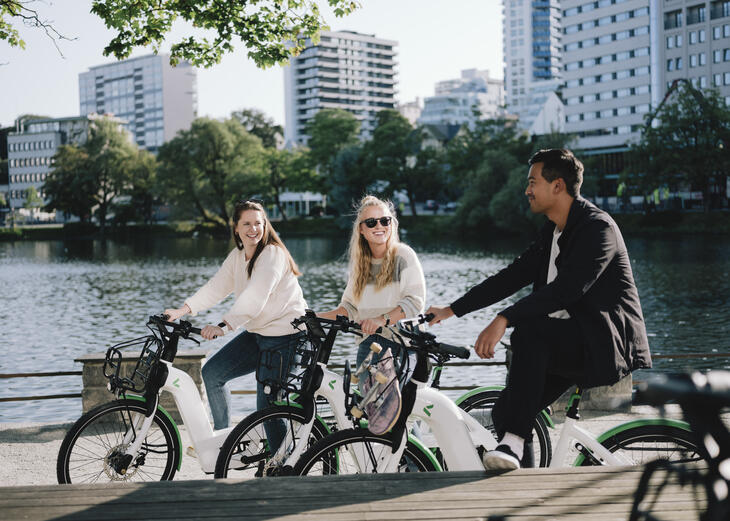 Tre personer på elsykkel foran Breiavatnet i Stavanger