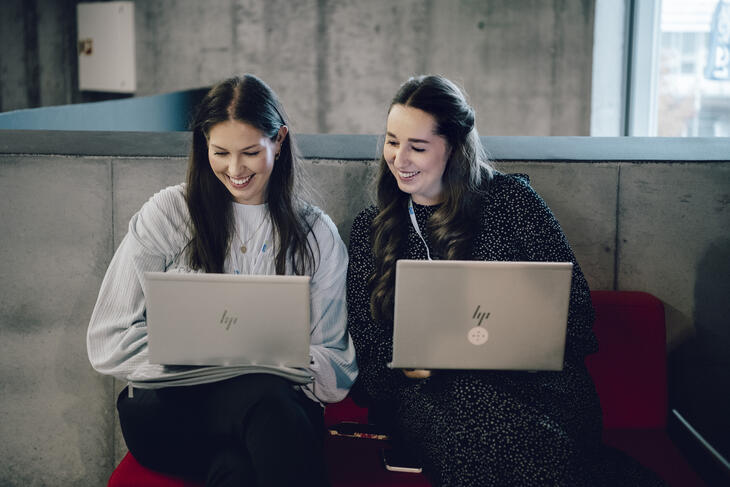 Two ladies sitting with laptops
