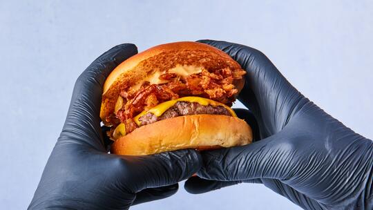 To hanskekledde hender holder en burger
