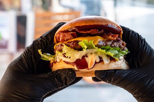 En burger på nært hold holdt av to hender med svarte hansker.