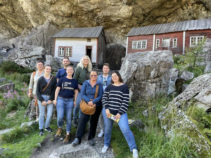 People on a viewing tour pose in front of the two wooden houses in Jøssingfjorden. Helleren