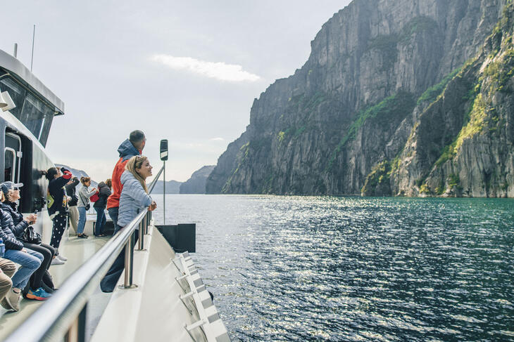 Personer på båttur med fjord- og fjellutsikt