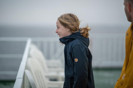 A girl out on deck on a ferry. Windy, she looks a bit cold