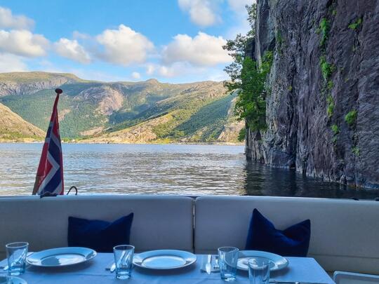 A table dressed for a meal onboard a yacht cruise with beautiful norwegian fjord views.