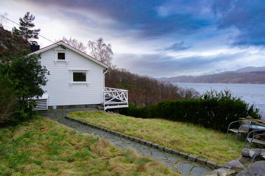 Lauvvik Fjordhytte - holiday home located near a fjord. Facade of the home with a terrace and view of fjord