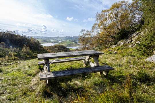 A wooden picnic bench and table with views on the hike in Lima to mountain Eikefjellet