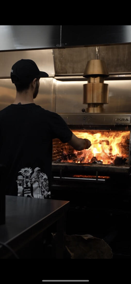 man cooking with flames at a burger restaurant