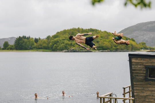 To menn hopper ut i vannet fra badstueflåte
